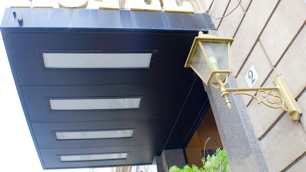 A hotel sign with the word "HOTEL" in large letters, a modern entrance with a black facade, and a decorative light fixture. - Grand Hotel Olympic (Rome)