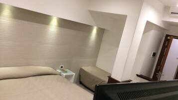 A hotel room with a bed, a bedside table, a TV, and a door.