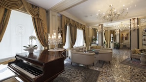 A luxurious living room with a grand piano, elegant sofas, and a chandelier. - Hotel Riviera (Venice)