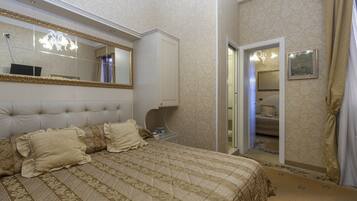 Une chambre à coucher avec un grand lit, une armoire, un miroir et une porte donnant sur une autre pièce.