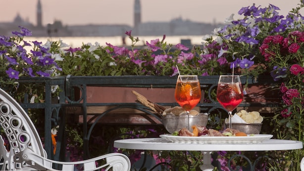 A table with a drink, snacks, and a view of a city skyline. - Hotel Riviera (Venice)