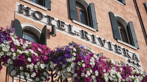 A building with the sign "HOTEL RIVIERA" and a balcony with purple and white flowers. - Hotel Riviera (Venice)