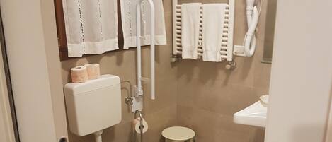 A modern bathroom with a toilet, bidet, towel rack, and a small sink.