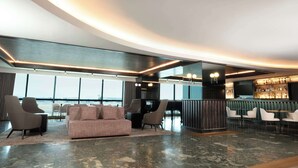 A modern lounge area with seating, a bar, and large windows offering a view.