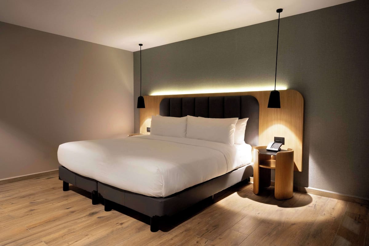 Un dormitorio moderno con una cama grande, mesitas de noche y un teléfono en la pared.
