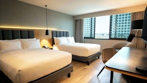 A hotel room with two beds, a desk, and a chair.
