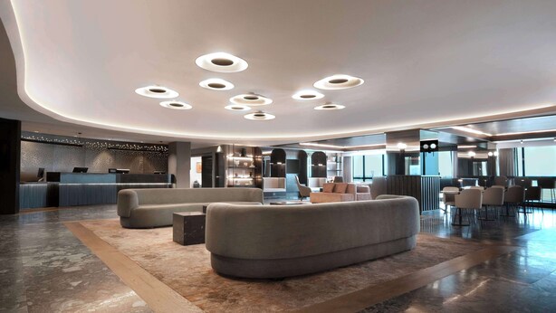 A modern lobby with a reception desk, seating area, and a large window providing a view.