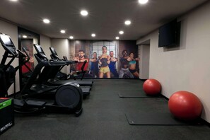 Ein Fitnessstudio mit Laufbändern, Gymbällen und einer motivierenden Wandmalerei.