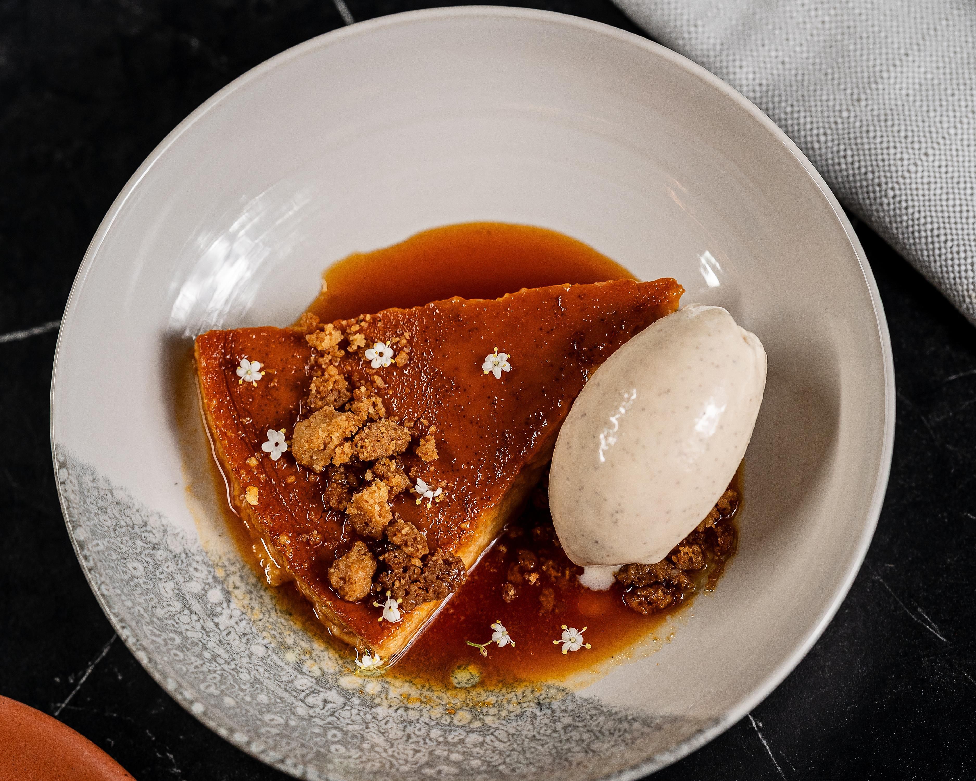 Ein Dessertteller mit karamellisierten Früchten, einer Kugel Eis und einem Sauce