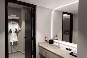 Ein modernes Badezimmer mit Marmorwaschbecken, einem großen Spiegel und einem Bademantel auf einem Haken.