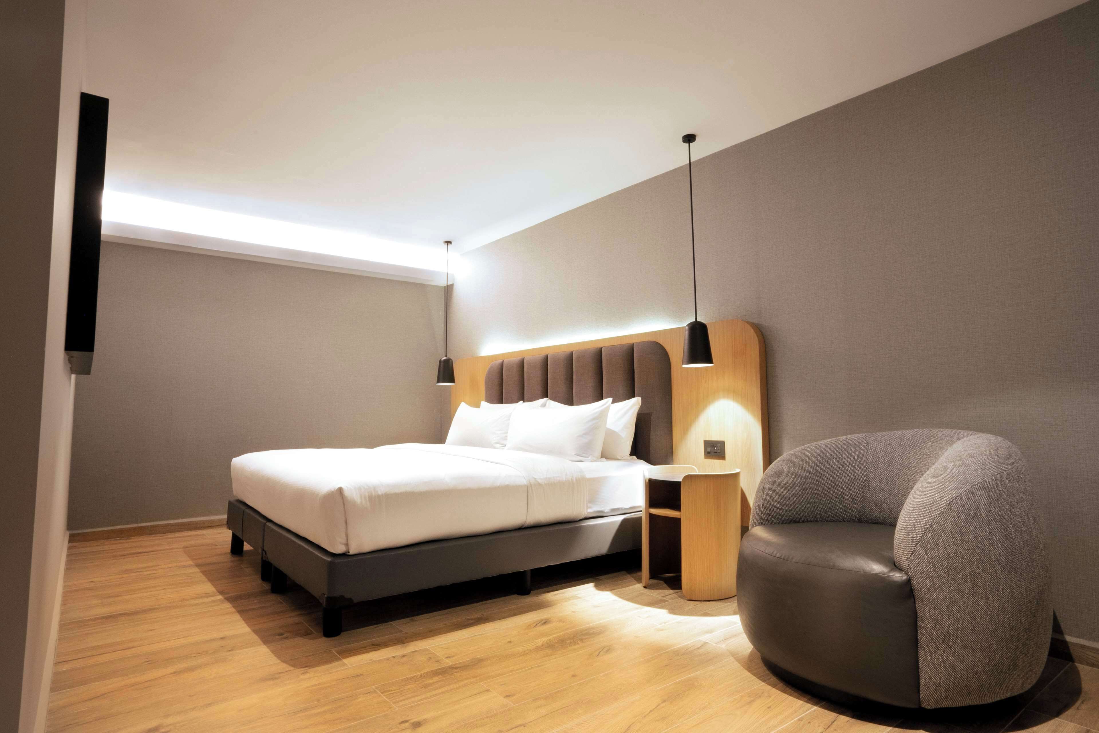 A modern bedroom with a bed, bedside table, and a chair.