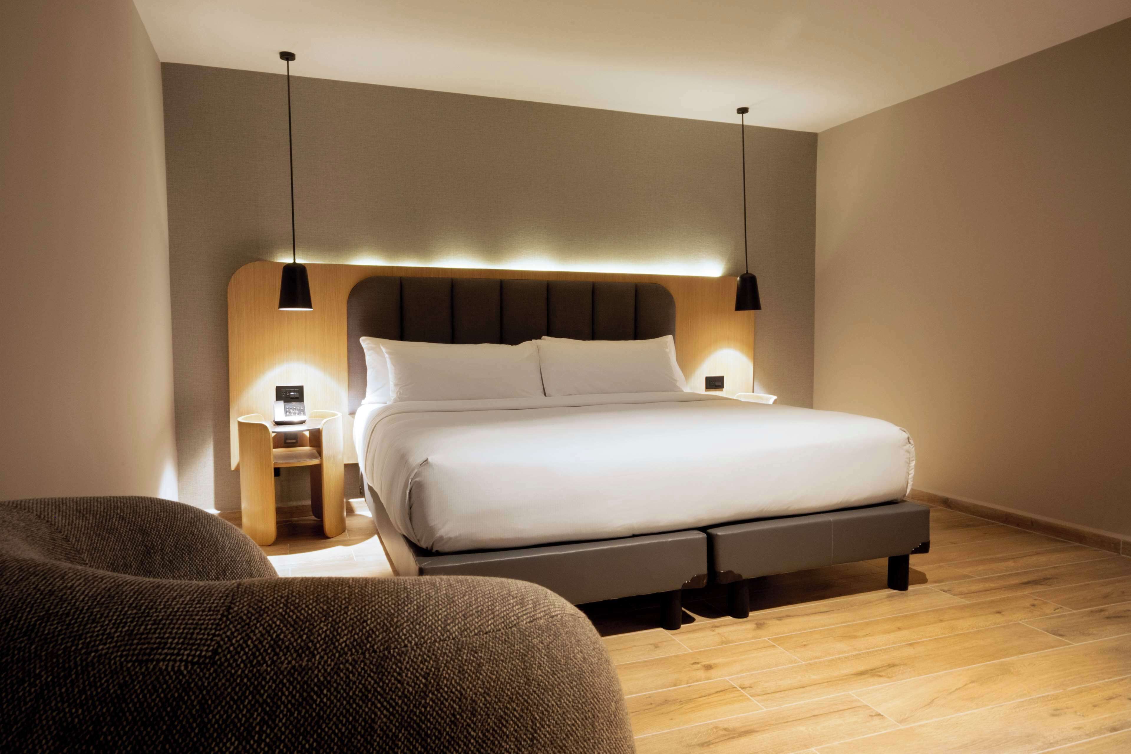 A modern bedroom with a large bed, bedside tables, and a wooden floor.