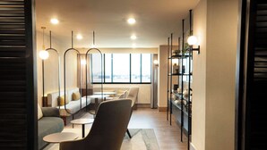 A modern lounge area with seating, tables, and a bookshelf.