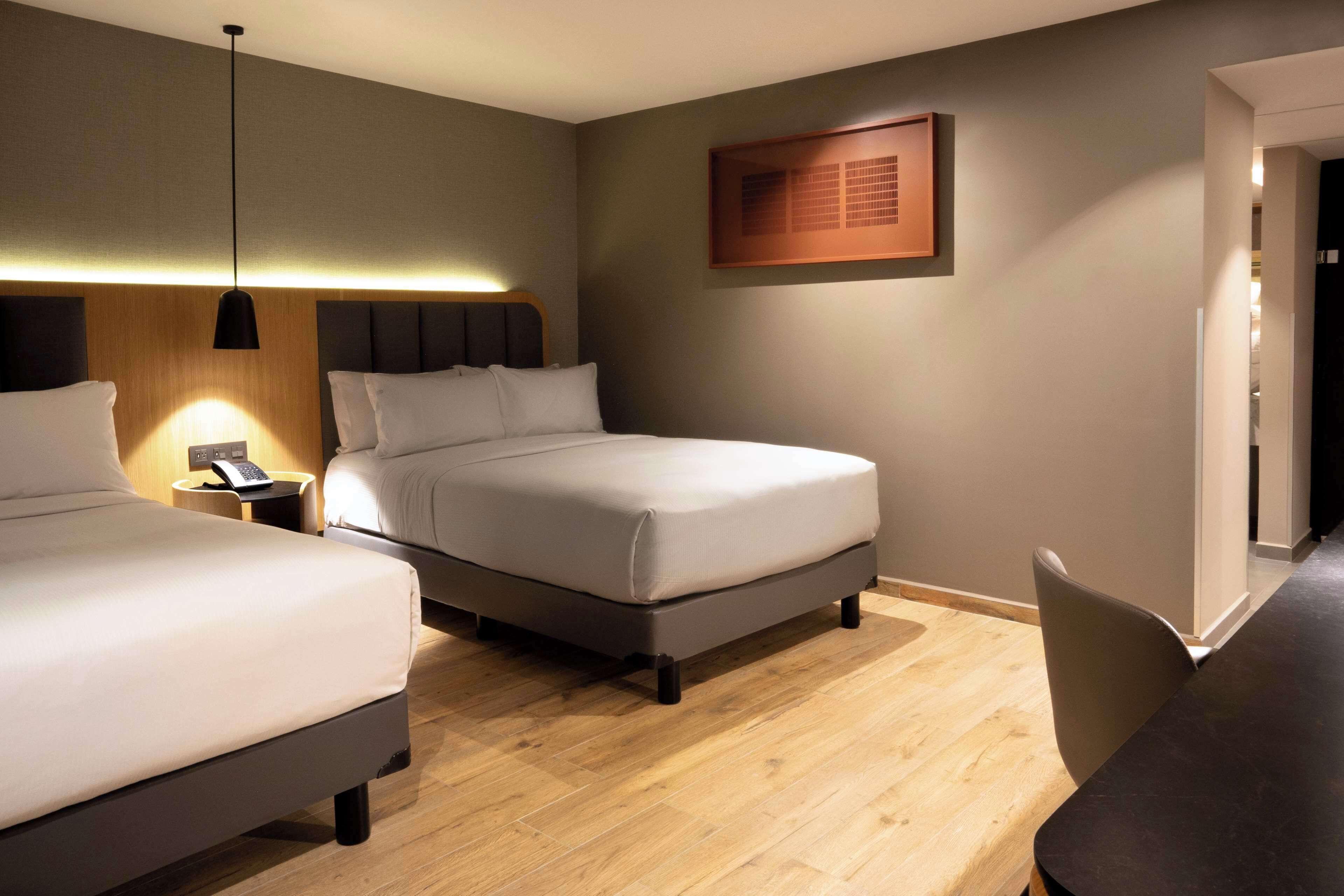 A hotel room with two beds, a desk, and a chair.