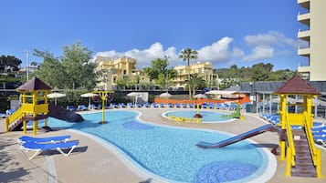 Relax by the resort pool, surrounded by lounge chairs and a children's play area.