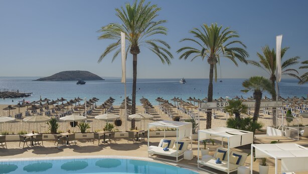 A poolside area with lounge chairs and umbrellas, a clear view of the sea, and a distant island. - Sol House Mallorca - Adults only (Calvia)