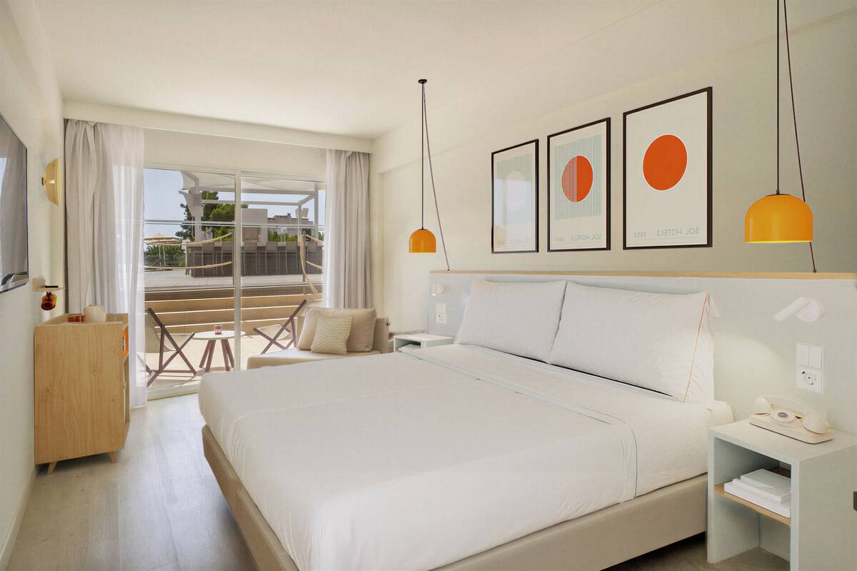 Habitación de hotel con una cama grande, un escritorio, una silla y un balcón con vistas.