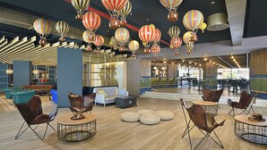 A spacious lobby with leather chairs, round tables, and a ceiling adorned with hot air balloons. - Sol Katmandu Park & Resort (Calvia)
