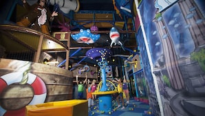 An indoor play area with a climbing structure, colorful play mats, and a mural of a sea scene. - Sol Katmandu Park & Resort (Calvia)