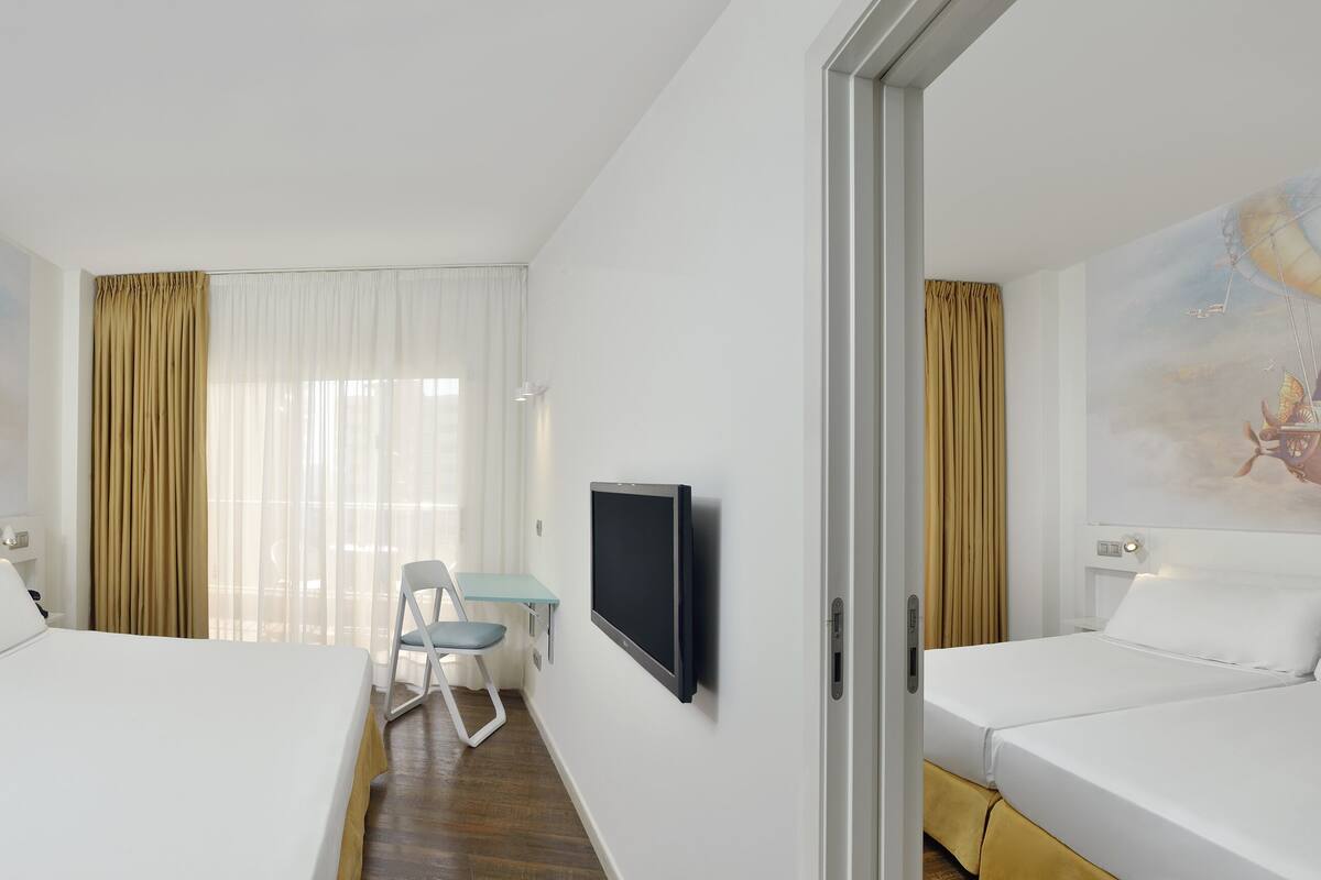 A hotel room with two beds, a TV, a desk, and a chair.