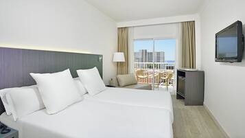 Habitación de hotel con una cama grande, televisión, balcón con una silla y vistas a la ciudad.