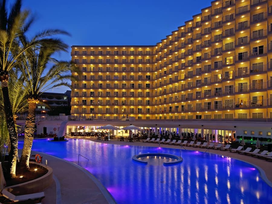 Un hotel con una piscina grande, varios balcones y una zona de bar.