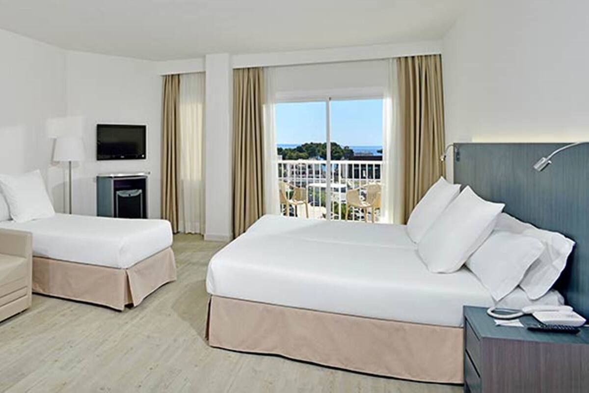 A hotel room with two beds, a sofa, a TV, and a balcony with a view.