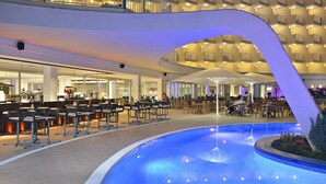 A hotel lobby with a pool, bar area, and outdoor seating. - Sol Guadalupe (Calvia)