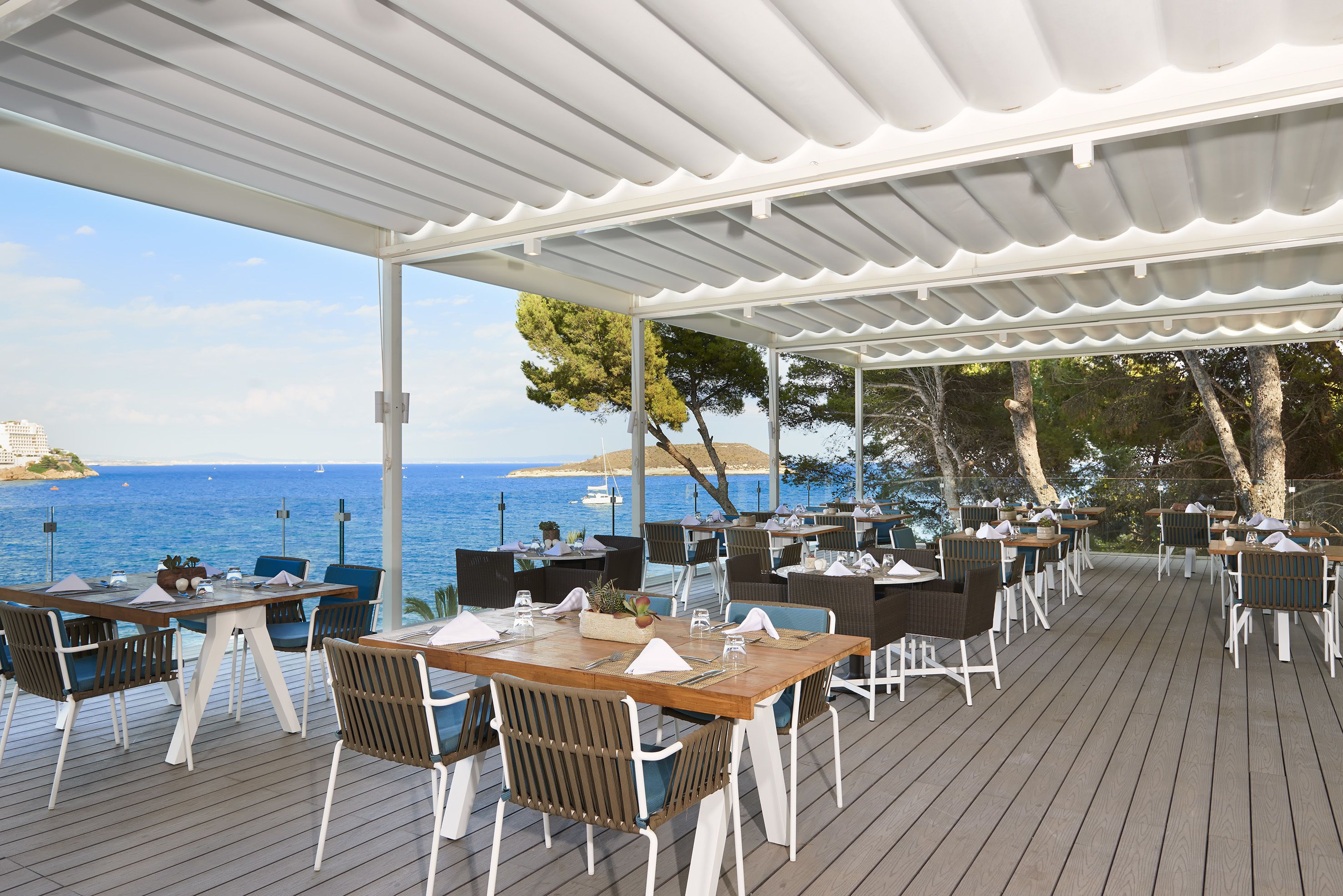 Un espace extérieur aménagé avec des tables et des chaises, offrant une vue sur la mer.