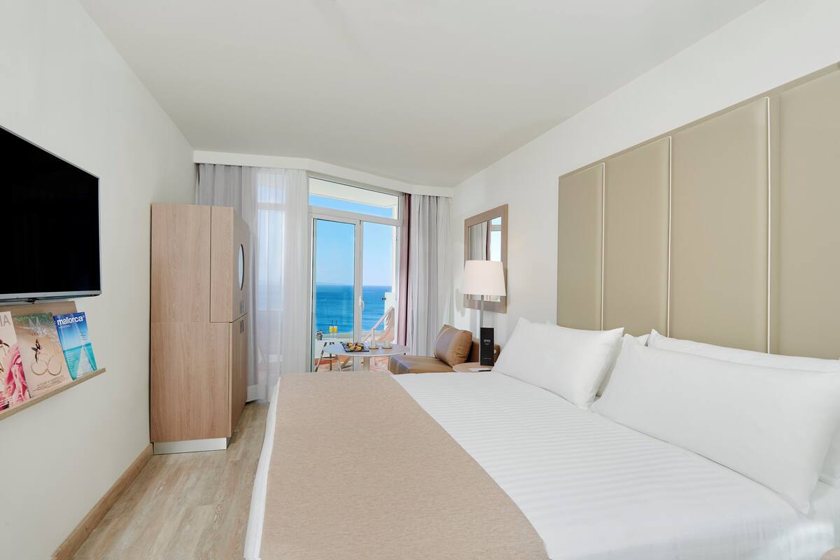 Habitación de hotel con una cama grande, televisión, escritorio y vista al océano.