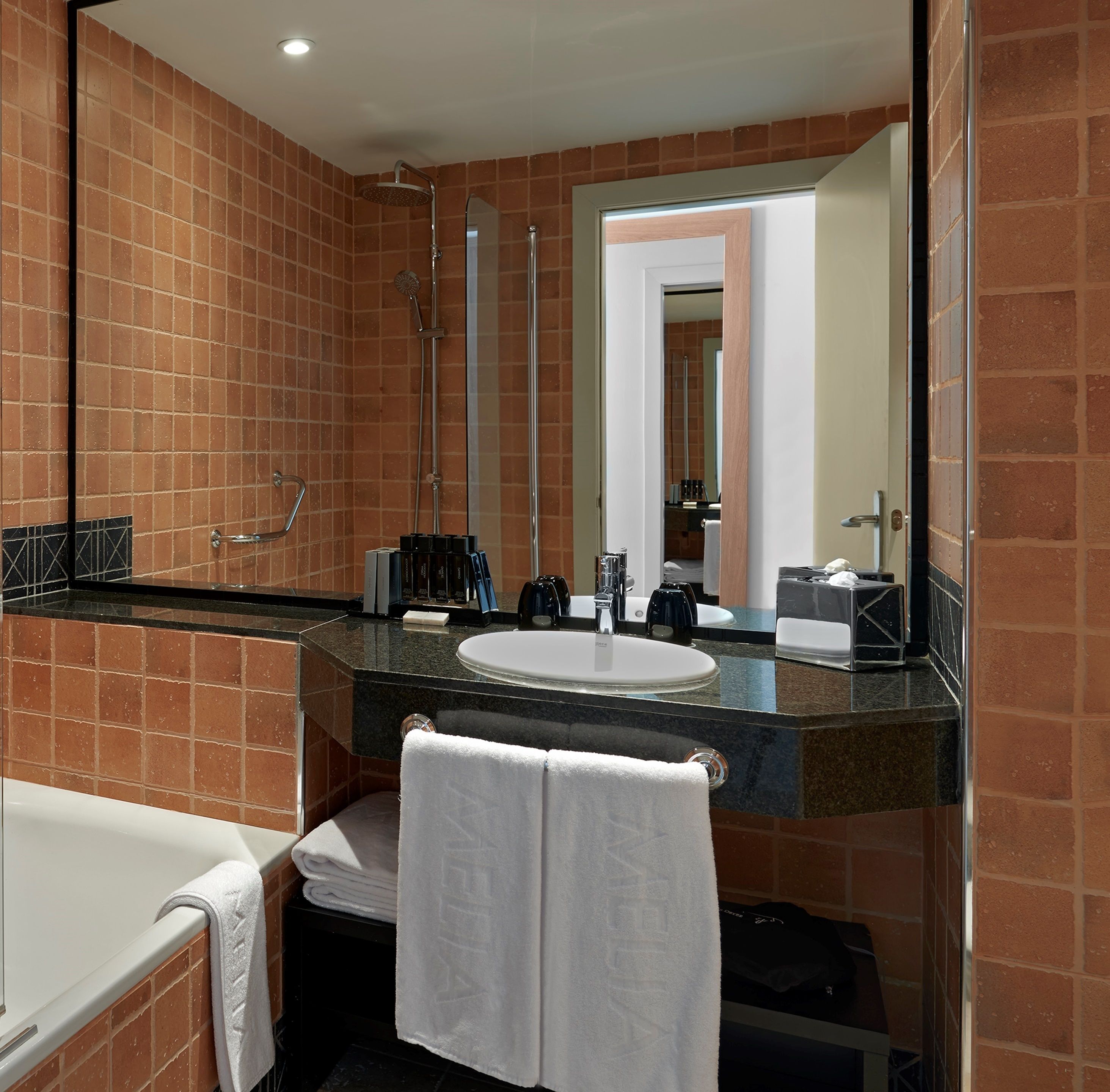 Un bagno con un ampio specchio, un lavandino, una doccia e una vasca da bagno.