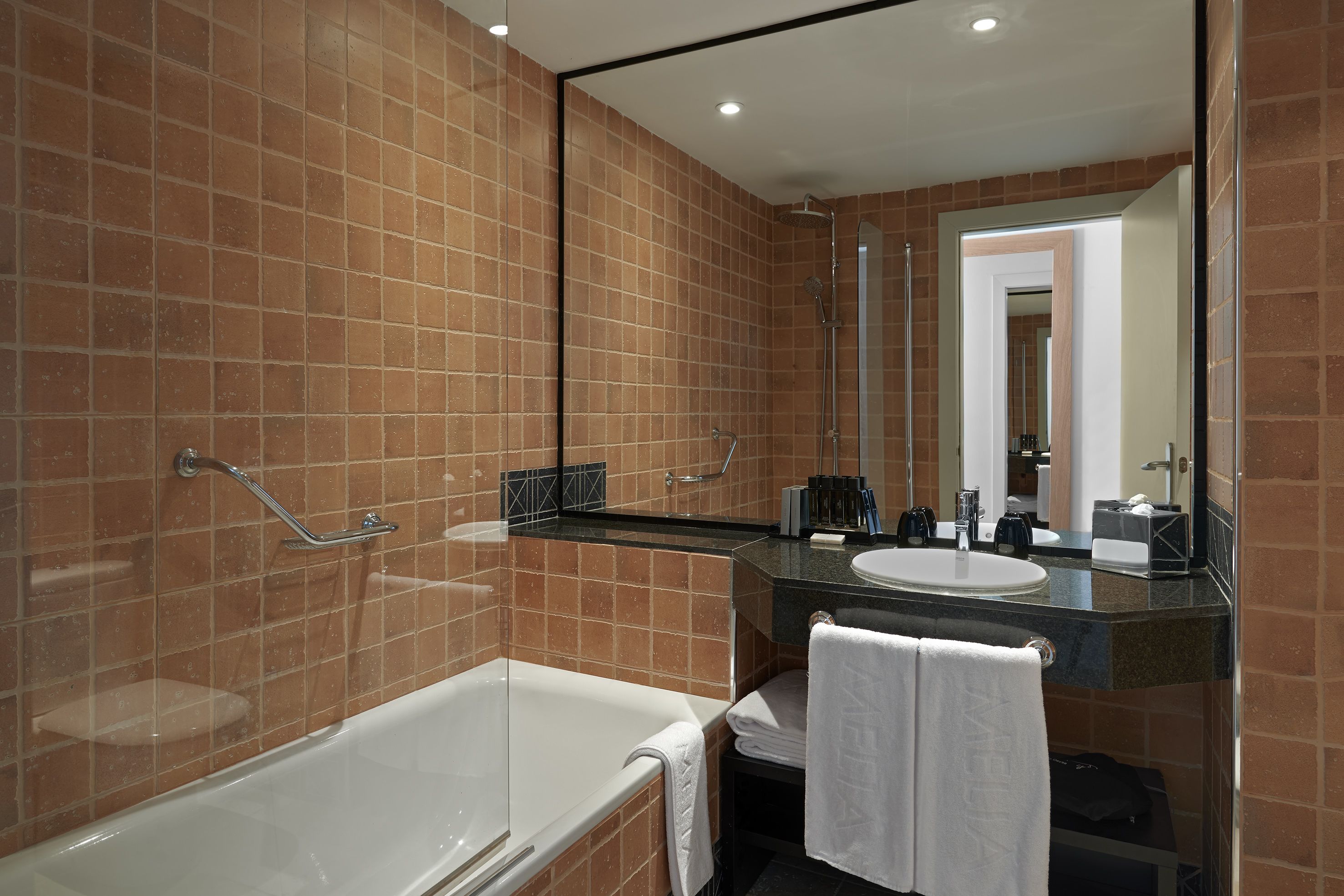 Een moderne badkamer met een badkuip, wastafel en douche.