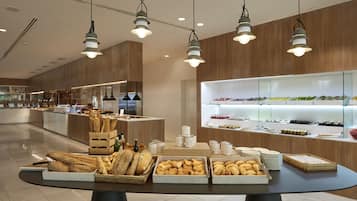 Een modern café met een verscheidenheid aan broden en gebak, gepresenteerd op een tafel, een houten toonbank en glazen vitrines met dranken.