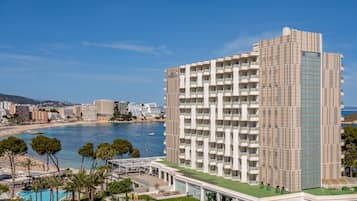 Un hotel de altura con varios balcones, una zona de piscina y vistas al mar.