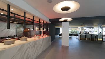 A modern kitchen with a marble countertop, overhead lighting, and a view into the dining area.