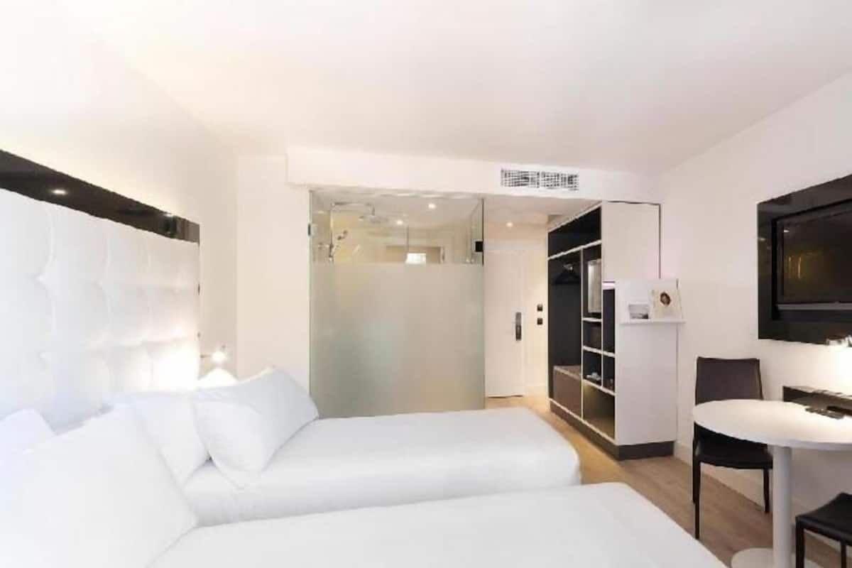 Quarto de hotel moderno com uma cama grande, uma escrivaninha e uma televisão.