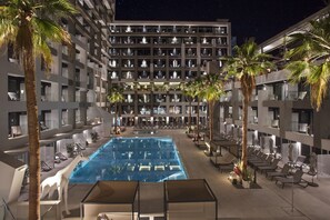 A hotel with a large indoor pool, multiple balconies, and palm trees.
