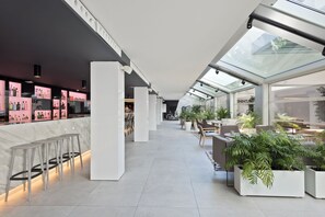 A modern hotel lobby with a bar area, seating, and potted plants. - INNSiDE by Meliá Palma Bosque (Palma de Mallorca)