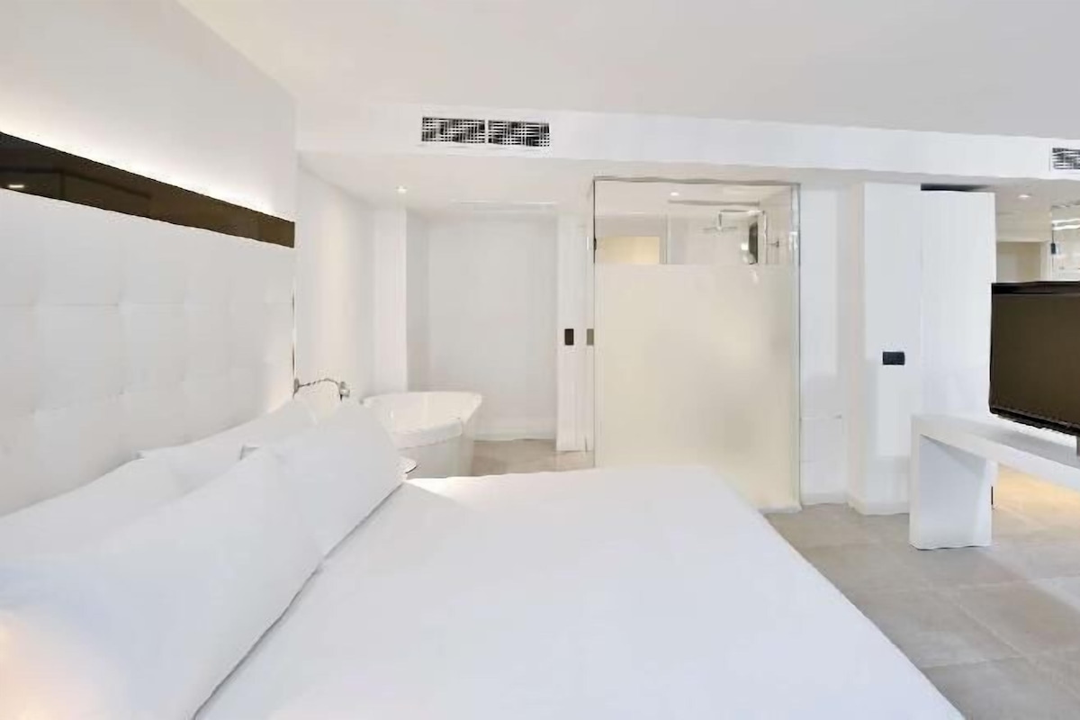 Een moderne hotelkamer met een groot bed, een televisie, een badkamer en een inloopkast.