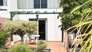 A courtyard with a white building, a green railing, and a table with chairs.