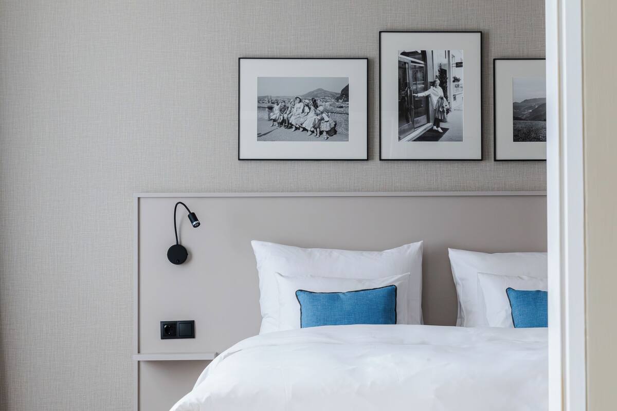 Una camera da letto con un letto, un comodino, una lampada e tre quadri appesi al muro.