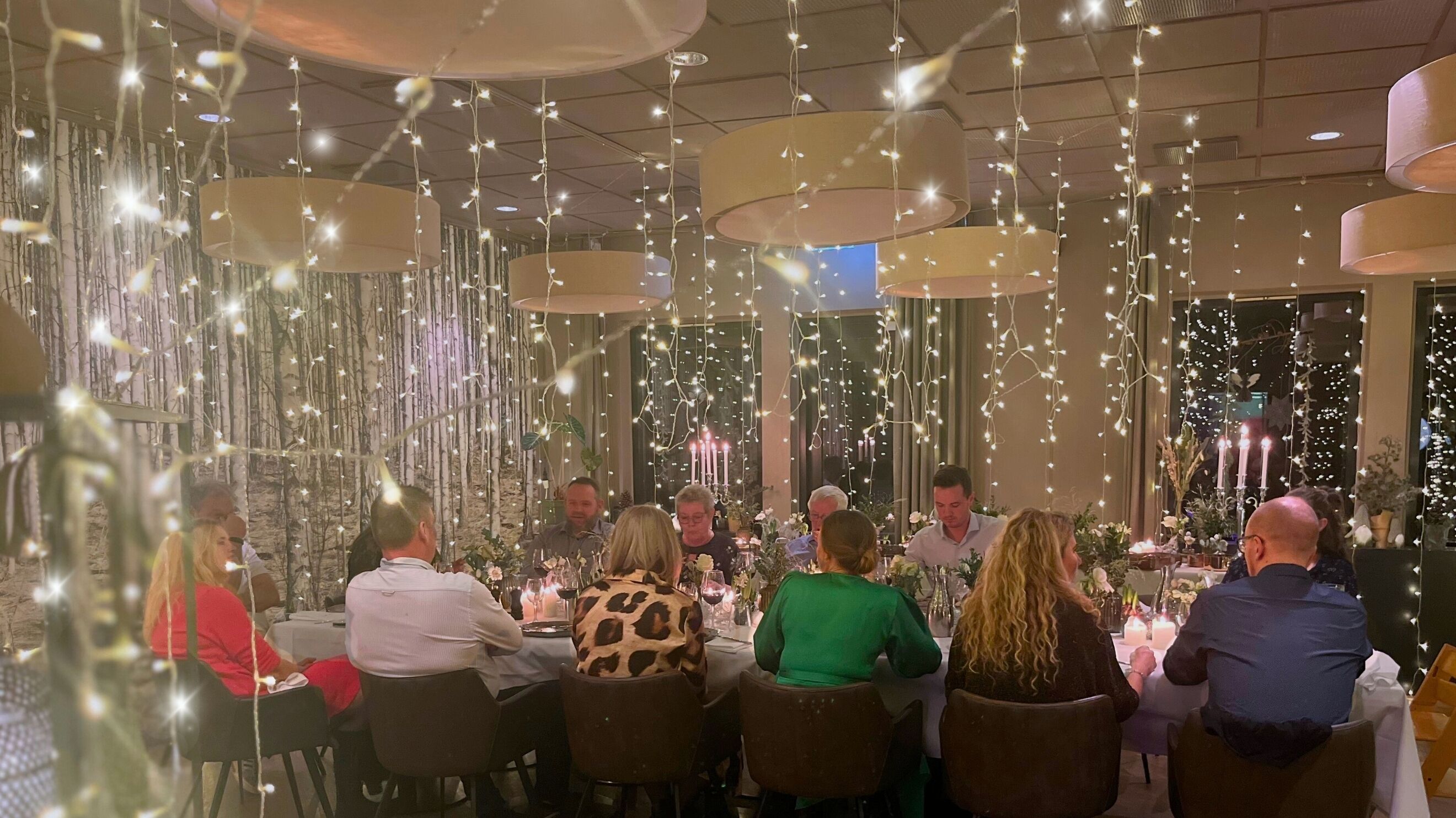 A restaurant with hanging string lights and candlelit tables.