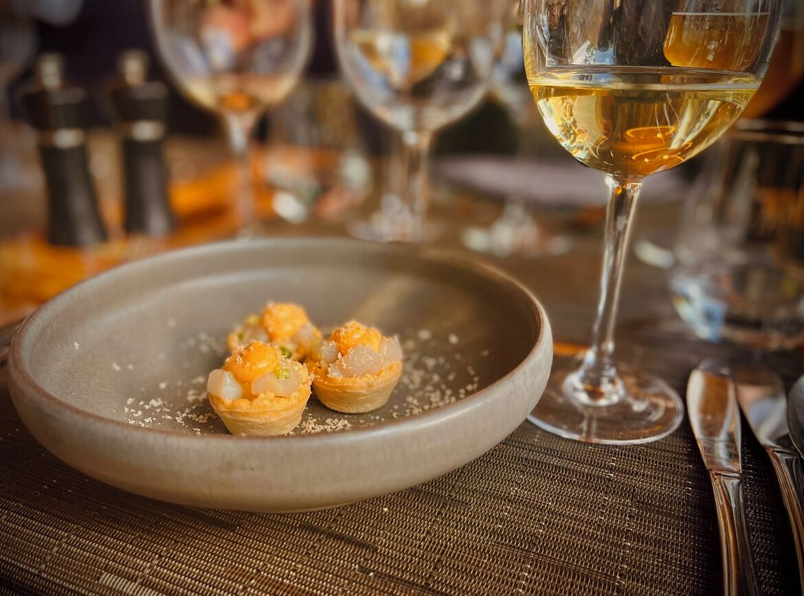 A plate of appetizers with a glass of white wine on a table.