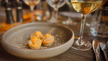 A plate of appetizers with a glass of white wine on a table.
