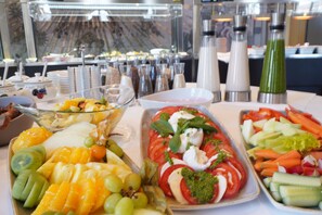 Un bufé con frutas, verduras y una ensalada.