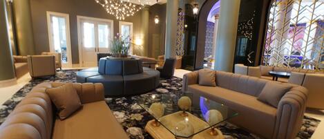 A spacious lobby with a large seating area, a glass coffee table, and a decorative chandelier.