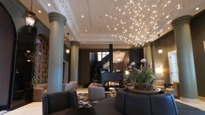 A lobby with a fireplace, sofas, and a chandelier. - Lumière Boutiquehotel im Fürstenhof Leipzig (Leipzig)