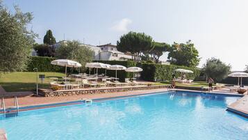 Una piscina al aire libre, sombrillas, sillones reclinables de piscina