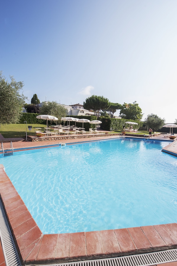 Una piscina al aire libre, sombrillas, tumbonas