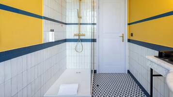 Un baño con ducha, paredes de azulejos y piso estampado.